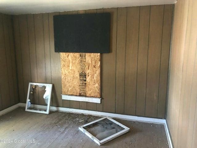 spare room with wooden walls, baseboards, and wood finished floors