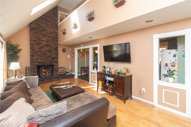 living room with a stone fireplace, light wood-type flooring, and high vaulted ceiling