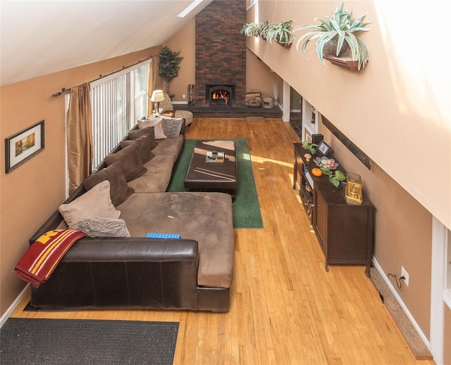 living room featuring a fireplace, light hardwood / wood-style floors, and vaulted ceiling