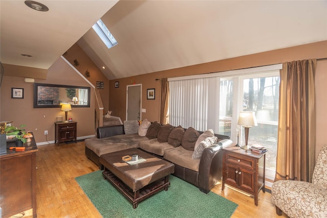 living room with lofted ceiling with skylight and light hardwood / wood-style flooring