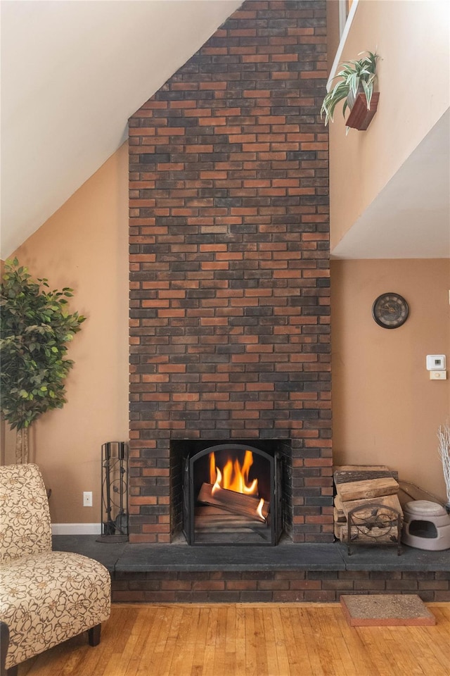 living room with a fireplace, wood-type flooring, and vaulted ceiling