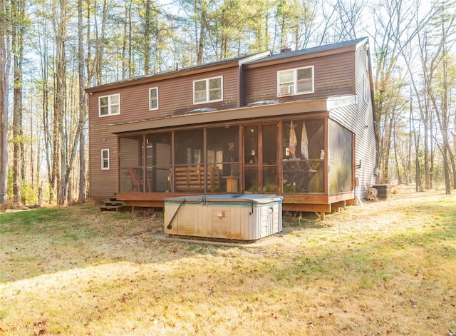 back of property with a sunroom, cooling unit, a yard, and a hot tub