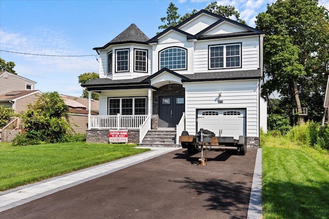 view of front of home featuring a garage, covered porch, and a front yard