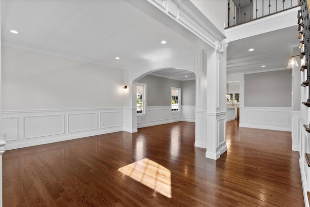 unfurnished living room with ornate columns, crown molding, and dark wood-type flooring