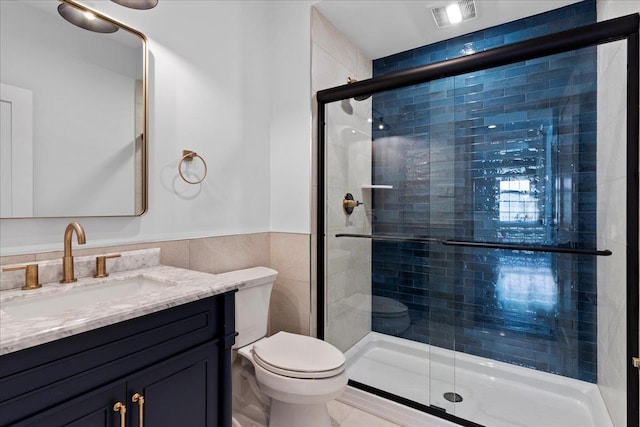 bathroom with tile walls, vanity, an enclosed shower, and toilet