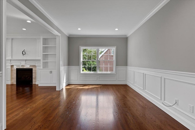 unfurnished living room featuring built in shelves, dark hardwood / wood-style flooring, ornamental molding, and a fireplace