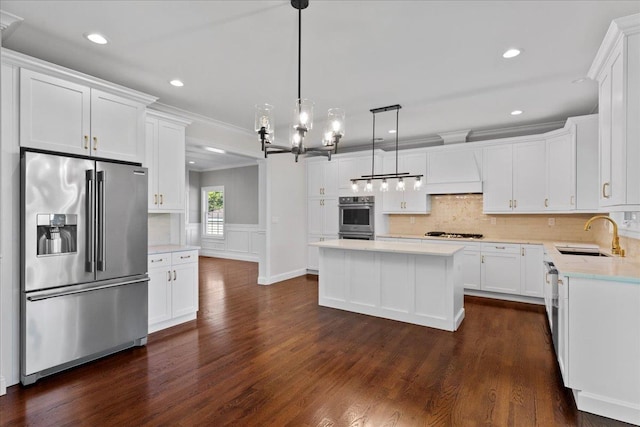 kitchen with appliances with stainless steel finishes, dark wood-type flooring, pendant lighting, and sink