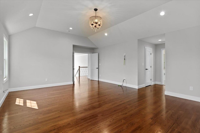 empty room featuring a chandelier, dark wood-type flooring, and vaulted ceiling