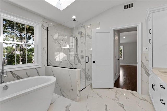 bathroom featuring plus walk in shower, vanity, a healthy amount of sunlight, and vaulted ceiling with skylight