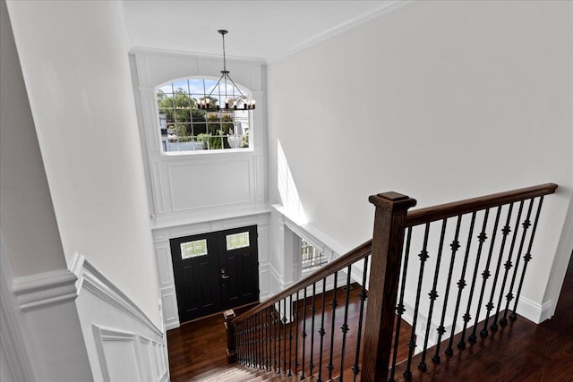 foyer featuring dark hardwood / wood-style flooring, crown molding, and an inviting chandelier