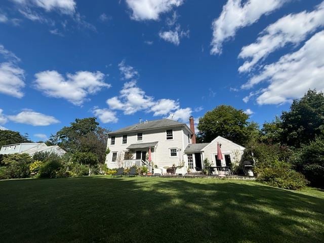 rear view of property featuring a yard and a chimney