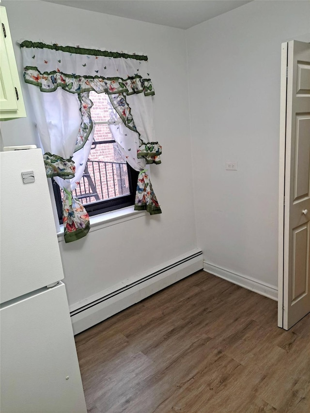 interior space with dark wood-type flooring and a baseboard heating unit