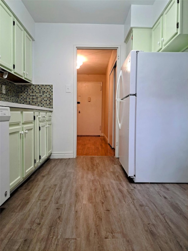 kitchen with decorative backsplash, light wood-type flooring, white appliances, and green cabinetry