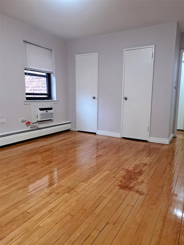 interior space with an AC wall unit, light hardwood / wood-style flooring, and a baseboard radiator