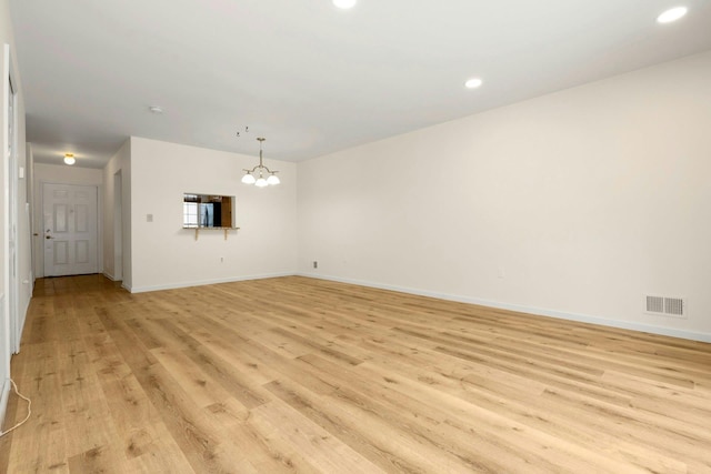 unfurnished living room featuring light wood-type flooring and an inviting chandelier