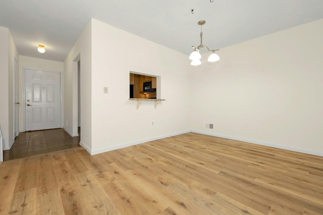 unfurnished dining area with a notable chandelier and light wood-type flooring