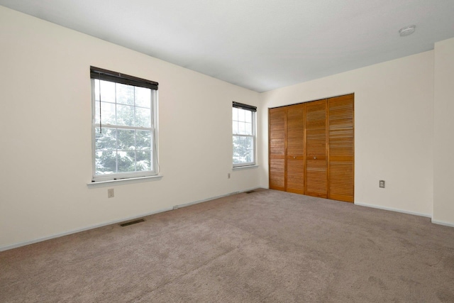 unfurnished bedroom with light colored carpet and a closet