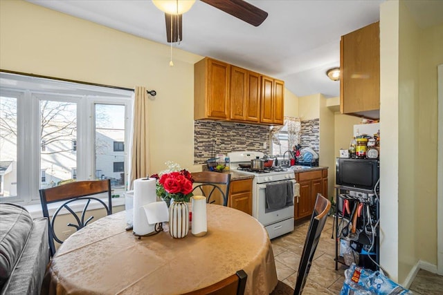 kitchen with ceiling fan, sink, decorative backsplash, light tile patterned floors, and white gas range oven