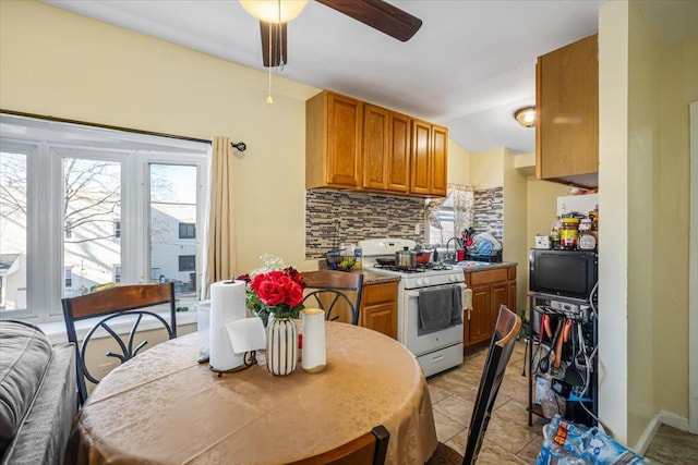 135-07 223rd St, Laurelton, NY 11413 - kitchen with white gas stove, a ceiling fan, backsplash, brown cabinets, and light tile patterned floors
