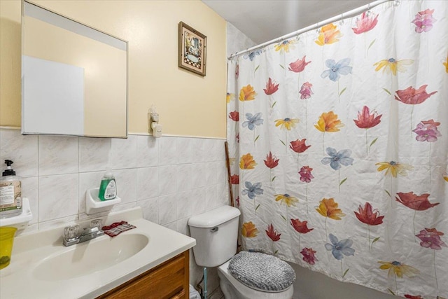 bathroom with a shower with shower curtain, vanity, toilet, and tile walls