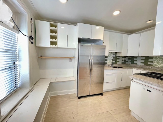 kitchen with white cabinetry, decorative backsplash, stainless steel fridge, and sink