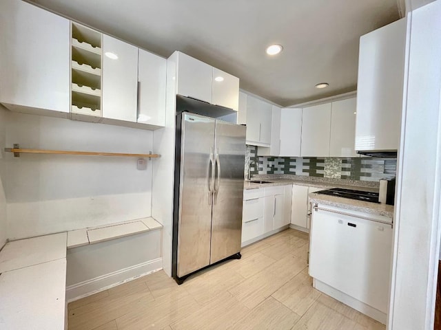 kitchen with backsplash, white cabinetry, stainless steel refrigerator, and sink