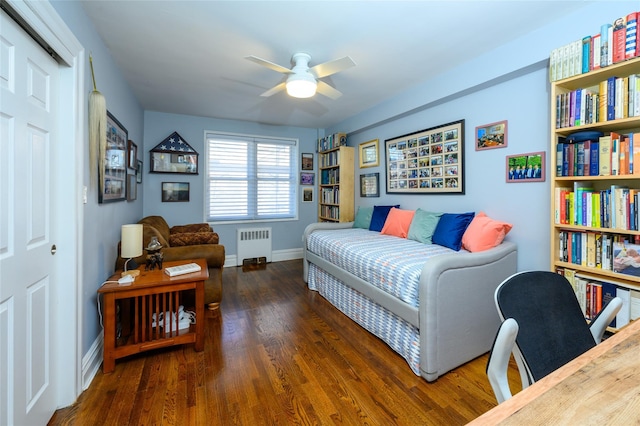 bedroom featuring ceiling fan, dark hardwood / wood-style flooring, radiator heating unit, and a closet