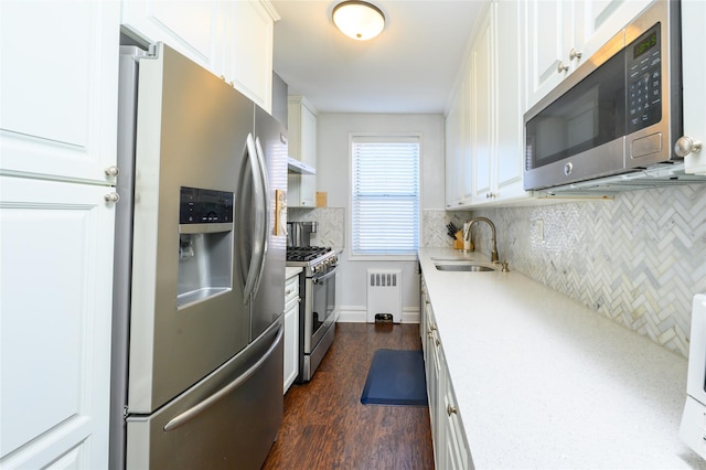 kitchen with white cabinetry, sink, radiator heating unit, stainless steel appliances, and dark hardwood / wood-style floors