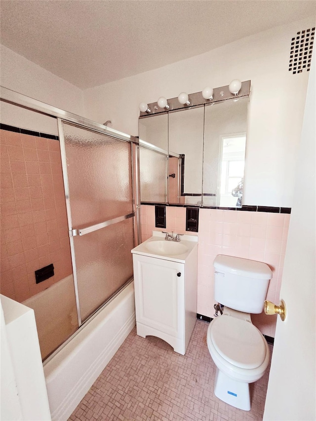 full bathroom with tile patterned floors, toilet, combined bath / shower with glass door, and vanity