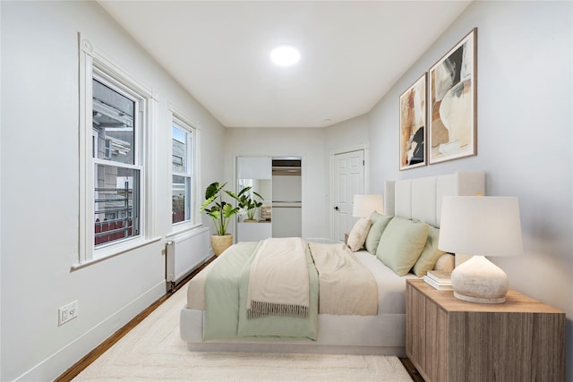 bedroom featuring radiator heating unit and wood-type flooring