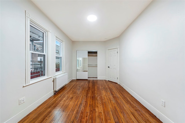 empty room with radiator heating unit and hardwood / wood-style flooring