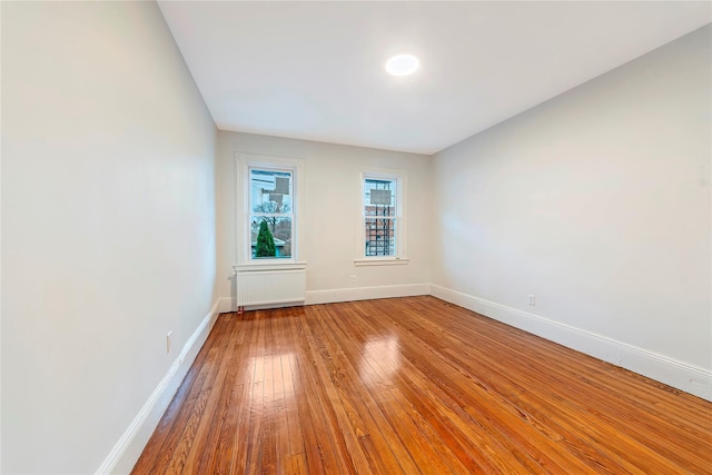 unfurnished room featuring hardwood / wood-style flooring and radiator heating unit