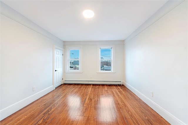 spare room with hardwood / wood-style flooring and a baseboard heating unit