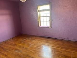 empty room featuring hardwood / wood-style floors and brick wall