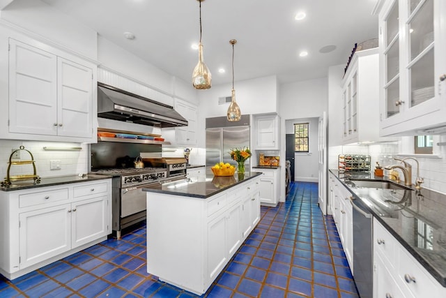 kitchen featuring sink, white cabinets, a center island, stainless steel appliances, and wall chimney range hood