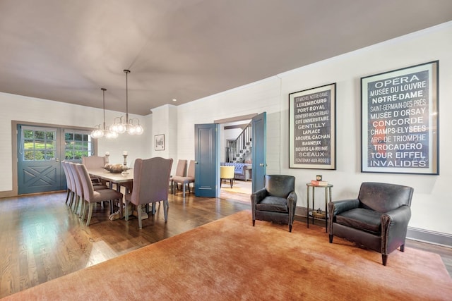 dining space with wood-type flooring, ornamental molding, and an inviting chandelier