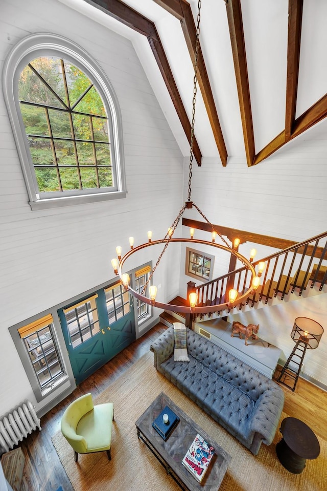 living room featuring an inviting chandelier, dark hardwood / wood-style flooring, and vaulted ceiling with beams