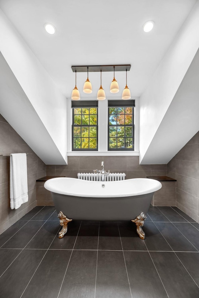 bathroom featuring tile patterned floors, radiator, a bathtub, and tile walls