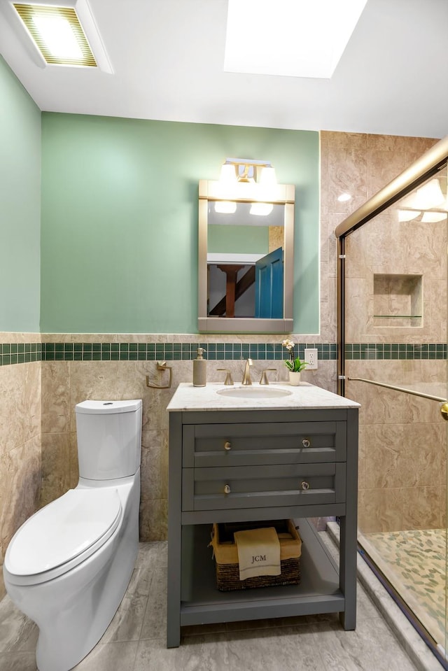 bathroom featuring toilet, a skylight, tile walls, a tile shower, and vanity