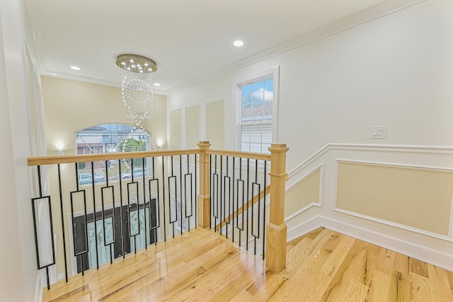 stairs with hardwood / wood-style flooring, ornamental molding, a wealth of natural light, and a chandelier