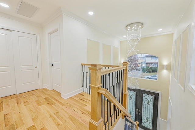 staircase featuring ornamental molding, hardwood / wood-style flooring, and a notable chandelier