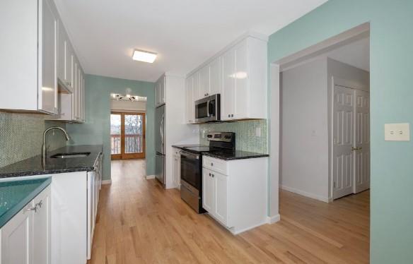 kitchen featuring white cabinetry, appliances with stainless steel finishes, sink, and light hardwood / wood-style flooring