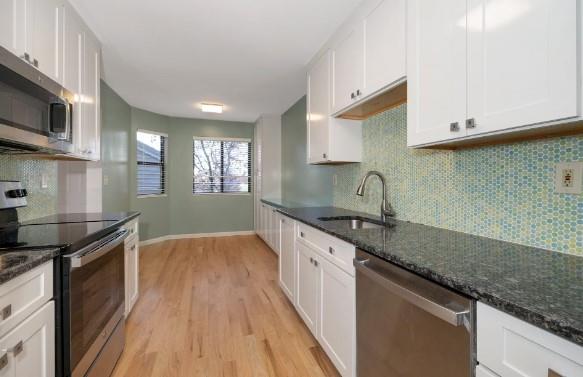 kitchen featuring white cabinetry, sink, stainless steel appliances, and dark stone countertops