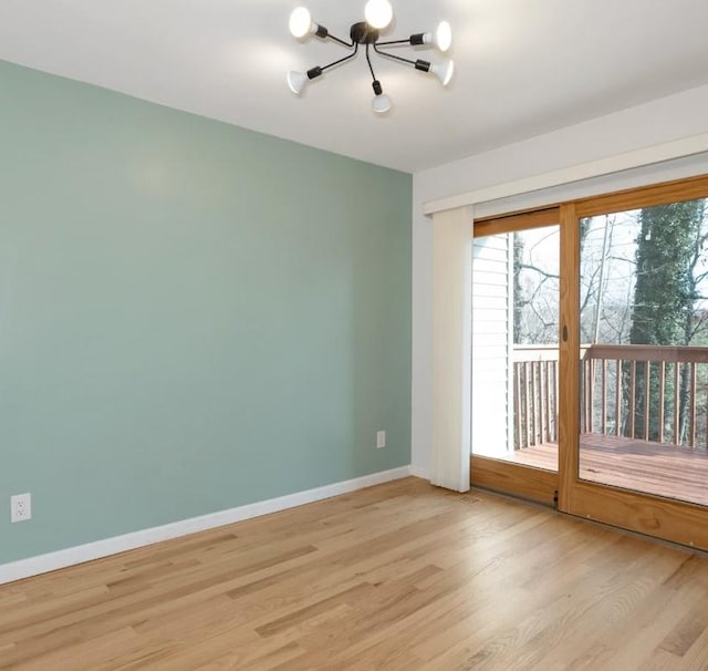 unfurnished room with a notable chandelier and light hardwood / wood-style flooring