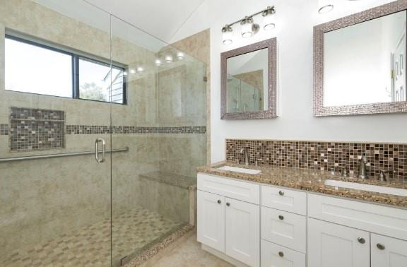 bathroom featuring lofted ceiling, backsplash, vanity, and a shower with shower door