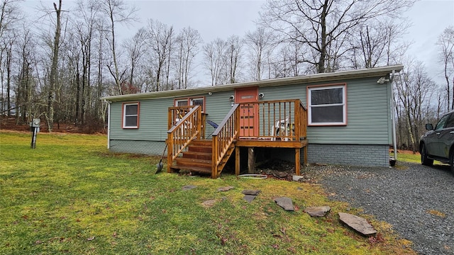 rear view of house featuring a wooden deck and a yard