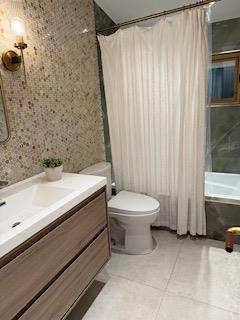 full bathroom featuring toilet, tile patterned flooring, vanity, and shower / bath combo with shower curtain