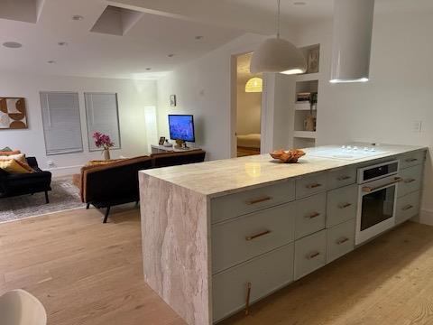 kitchen with gray cabinets, oven, light hardwood / wood-style floors, white stovetop, and hanging light fixtures