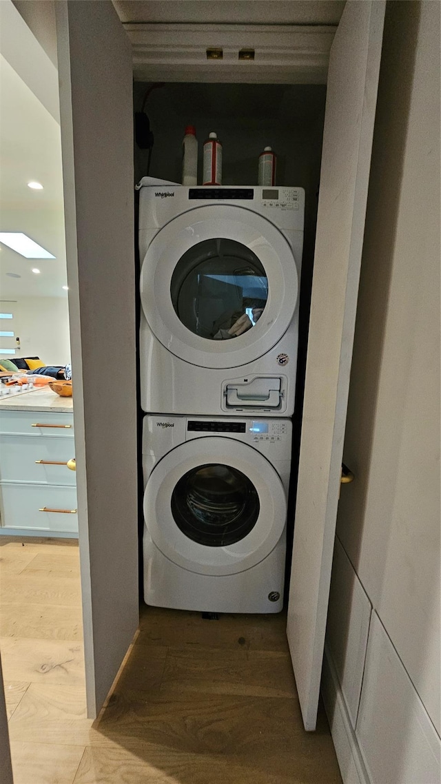 clothes washing area featuring hardwood / wood-style flooring and stacked washing maching and dryer