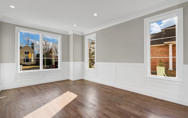 unfurnished room featuring ornamental molding, a healthy amount of sunlight, and hardwood / wood-style flooring